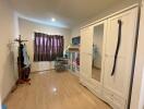 Well-lit bedroom with wooden floor, wardrobe, and children's decor