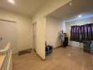 A view of a living area with wooden flooring, various storage bins, a coat rack, and curtains