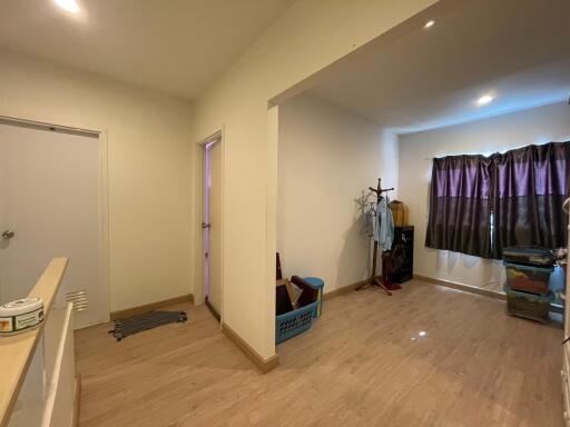 A view of a living area with wooden flooring, various storage bins, a coat rack, and curtains