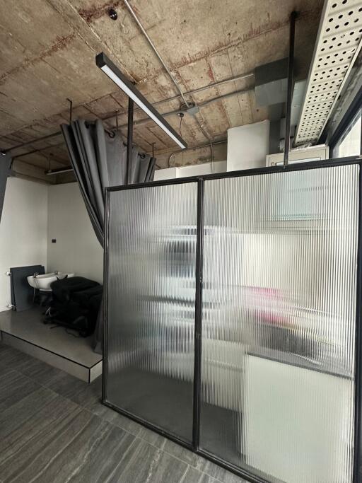 Modern bathroom with industrial ceiling and frosted glass partition