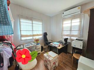 Bedroom converted into a workspace with office equipment and storage