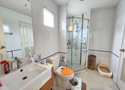 Modern bathroom with glass shower, sink, toilet, and window