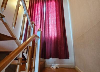 Staircase area with wooden railing and red curtains