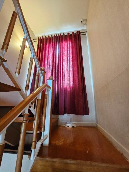 Staircase area with wooden railing and red curtains