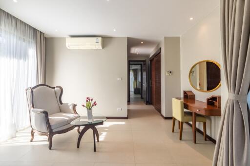 Living room with armchair, coffee table, desk with chair, and a wall-mounted mirror