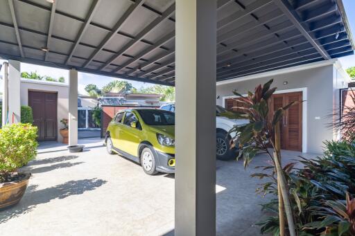 Covered parking area with two cars and surrounding plants