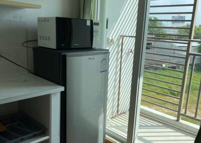 Modern kitchen area with a mini fridge, microwave, and access to a balcony.