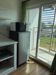 Modern kitchen area with a mini fridge, microwave, and access to a balcony.