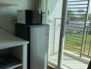 Modern kitchen area with a mini fridge, microwave, and access to a balcony.