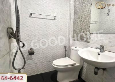 Modern bathroom with white tiles, shower, toilet, and sink