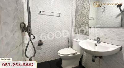 Modern bathroom with white tiles, shower, toilet, and sink