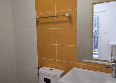 Modern bathroom with white fixtures and orange tile accent wall