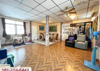 Spacious living room with wooden floor, seating area, dining table, ceiling fan, and decor