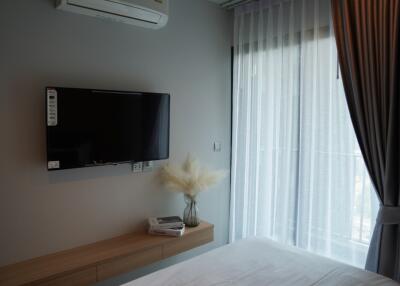 Bedroom with wall-mounted TV, air conditioner, and large window