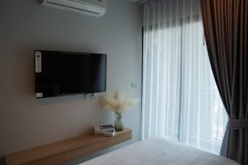 Bedroom with wall-mounted TV, air conditioner, and large window