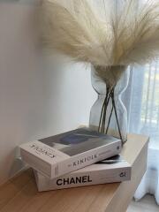 Close-up of a decorative side table with books and dried pampas grass