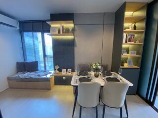 Modern dining area with a table set for four adjacent to a cozy window seat and decorative shelving