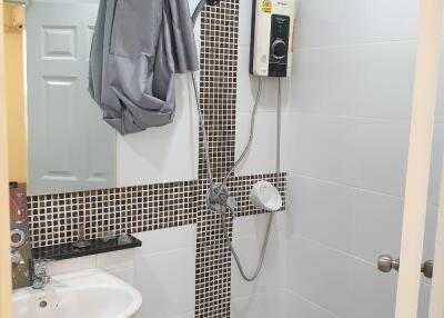 Bathroom with shower area, sink, and water heater