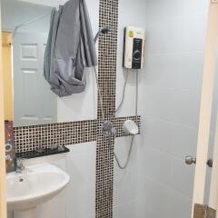 Bathroom with shower area, sink, and water heater