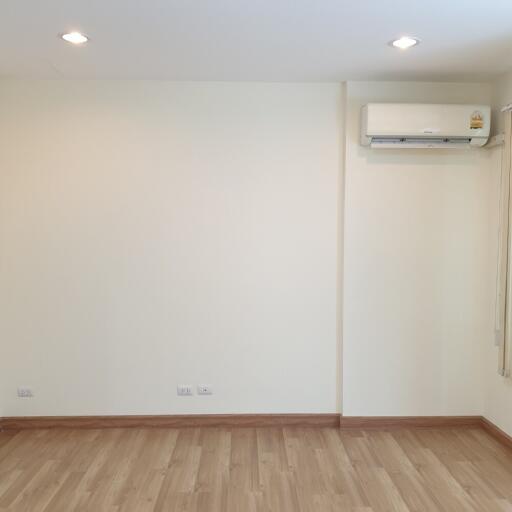 Spacious empty living room with wooden flooring and air conditioner