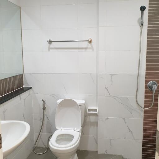 Modern bathroom with toilet, sink, shower, and towel rail