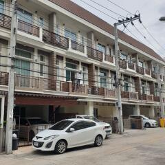 Street view of an apartment building with parking area and multiple balconies