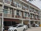 Street view of an apartment building with parking area and multiple balconies