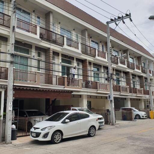 Street view of an apartment building with parking area and multiple balconies