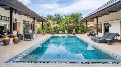 Outdoor pool with patio furniture and greenery