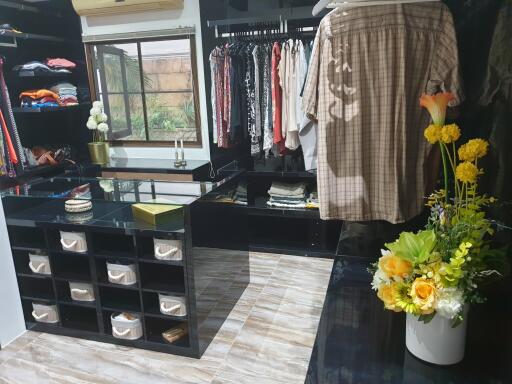 Spacious walk-in closet with clothing racks, shelves, and a floral arrangement.