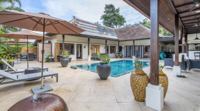 Luxurious outdoor pool area with lounge chairs and potted plants