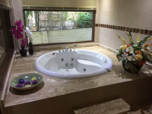 Spacious bathroom with a large jacuzzi tub and decorative flowers