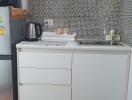 Compact kitchen with white cabinets and mosaic tile backsplash