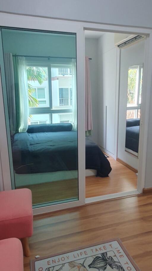 A cozy bedroom with glass sliding door, wooden flooring, and large windows