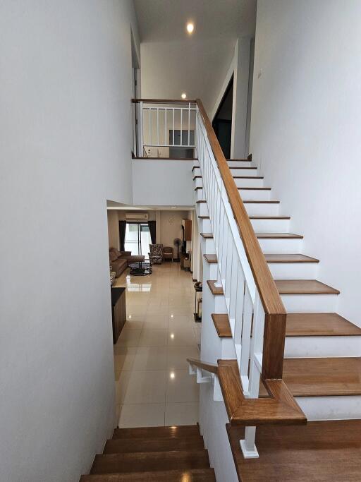 Bright and spacious interior staircase leading to an upper level overlooking a modern living area