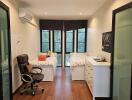 Bedroom with twin beds, modern office chair, dresser, and hardwood floors