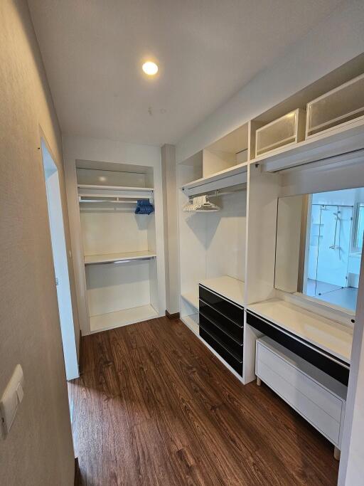 Spacious walk-in closet with built-in shelves, drawers, and a mirror