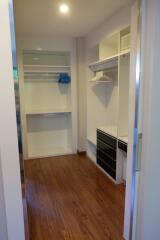 Walk-in closet with wooden flooring, built-in shelves, and drawers