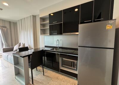 Modern kitchen area with black appliances and adjacent living space