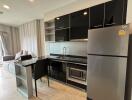 Modern kitchen area with black appliances and adjacent living space