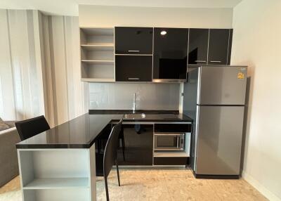 Modern kitchen with sleek black cabinetry, built-in appliances, and a refrigerator