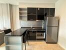 Modern kitchen with sleek black cabinetry, built-in appliances, and a refrigerator