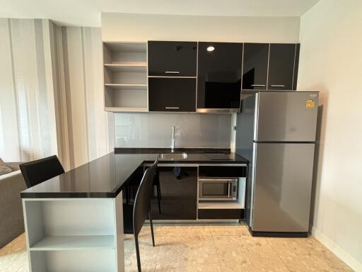 Modern kitchen with sleek black cabinetry, built-in appliances, and a refrigerator