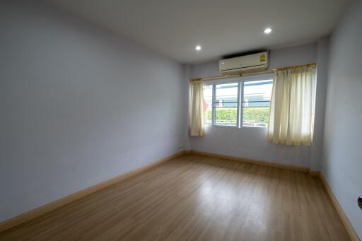 Spacious bedroom with wooden flooring, air conditioning, and large window