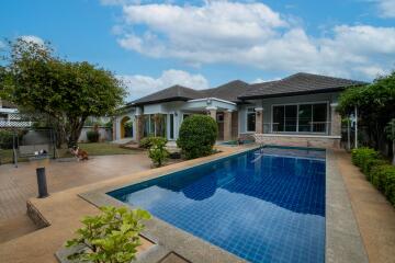 Outdoor area with a swimming pool and a house in the background