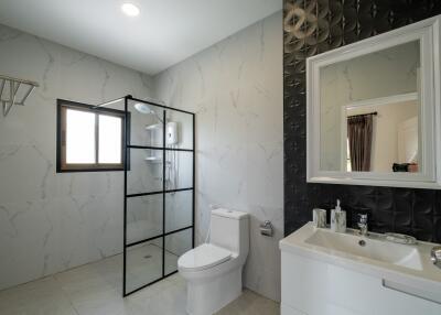 Modern bathroom with a glass shower, toilet, and vanity with mirror