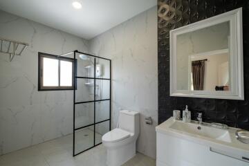 Modern bathroom with a glass shower, toilet, and vanity with mirror