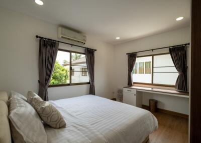 Well-lit bedroom with large windows, air conditioning, and a cozy bed