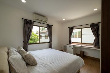 Well-lit bedroom with large windows, air conditioning, and a cozy bed