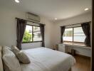 Well-lit bedroom with large windows, air conditioning, and a cozy bed